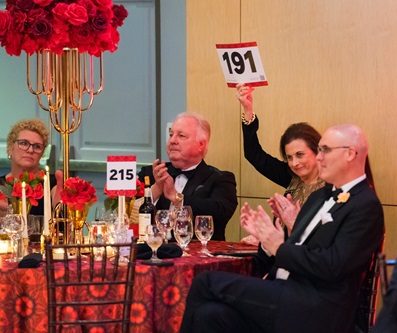 Woman in audience holding up bidder paddle number 191.